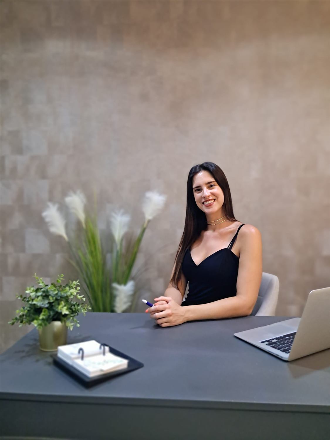 Ana María Quiñonero sonriendo, sentada en la mesa de su consulta